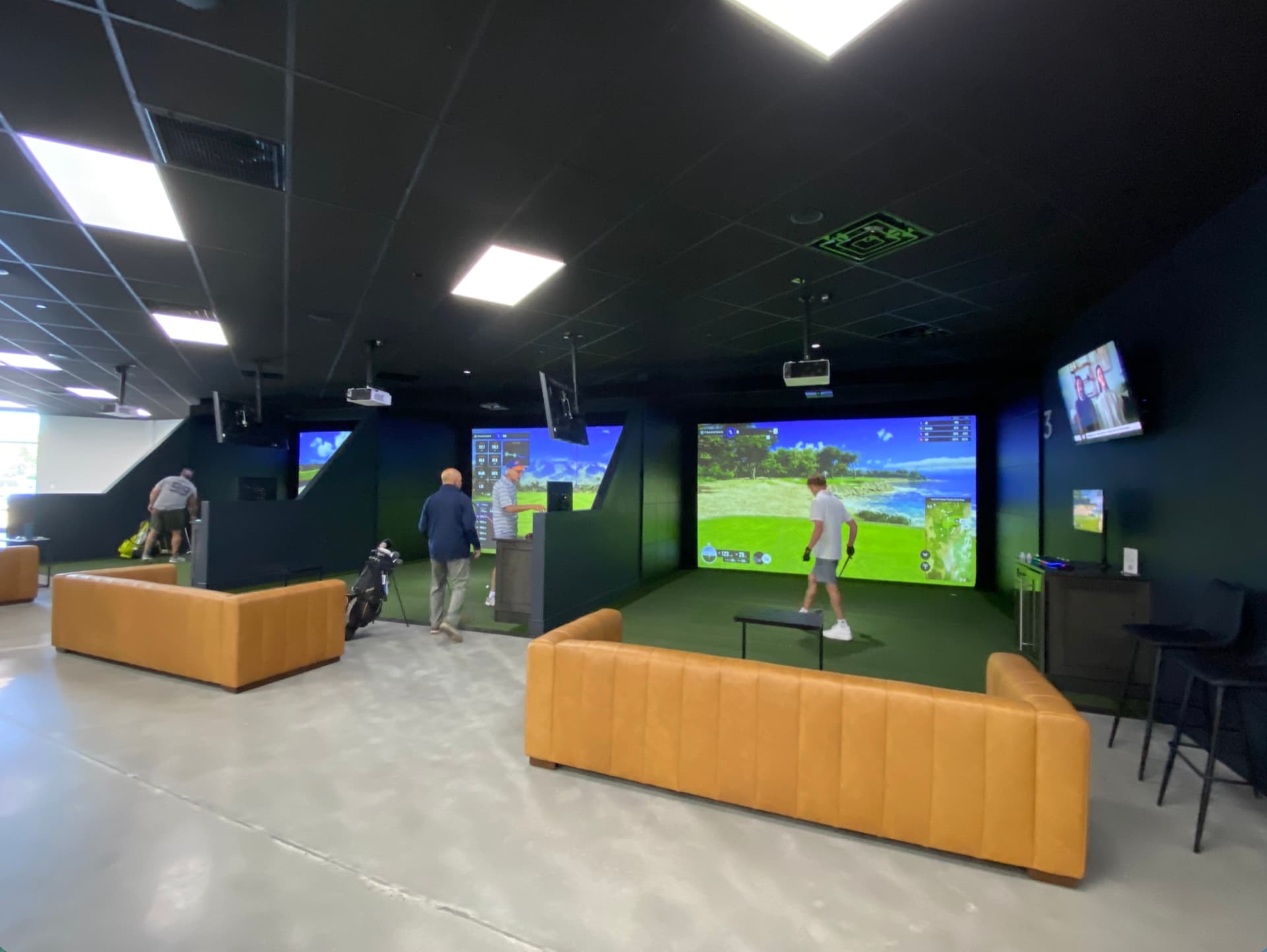 Golfers playing in the Trackman iO simulator bays at Unbound Golf in Branchburg, NJ