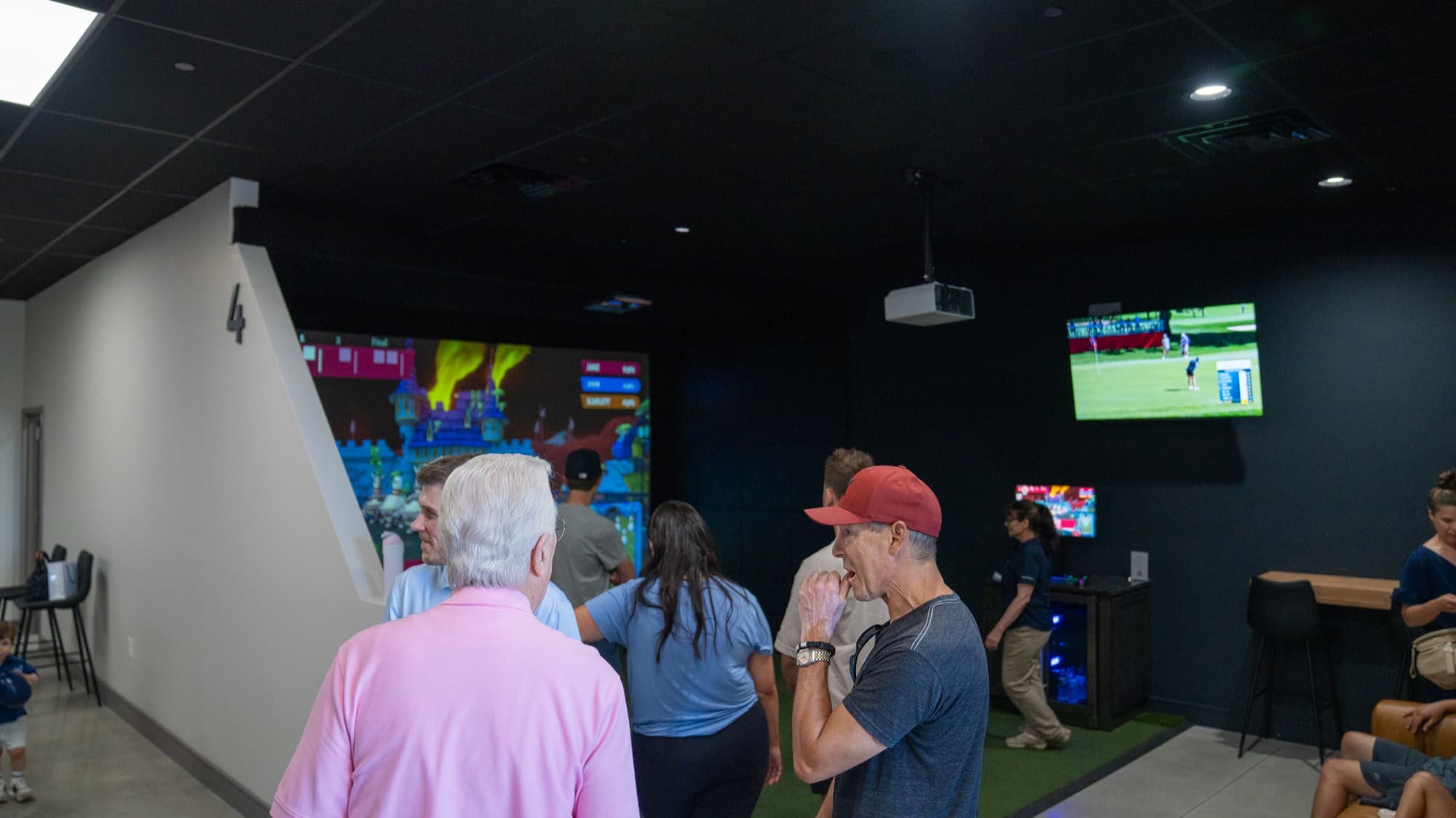 A group of friends playing together in a simulator bay at Unbound Golf