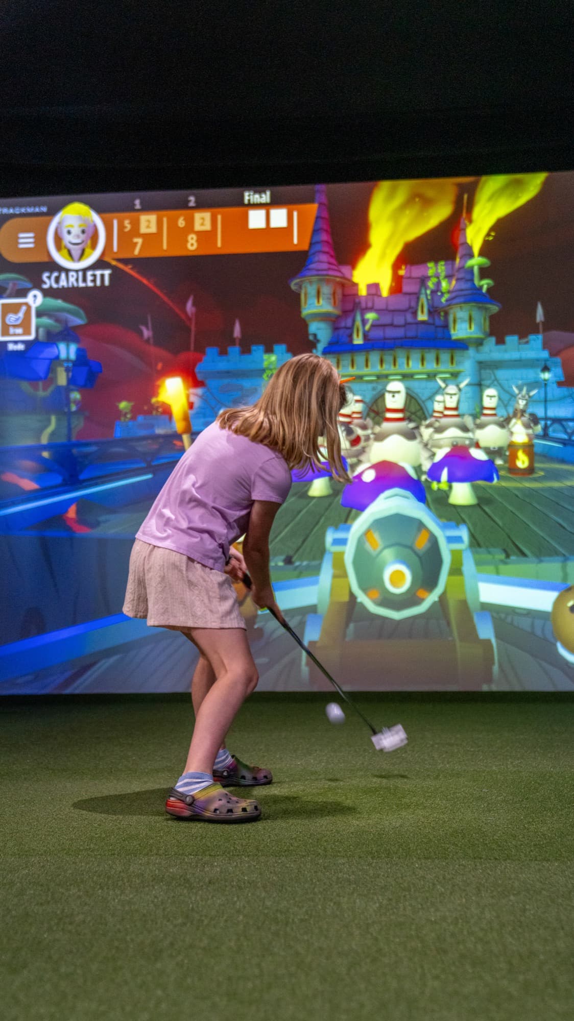 A child playing a kids’ game in a simulator bay at Unbound Golf
