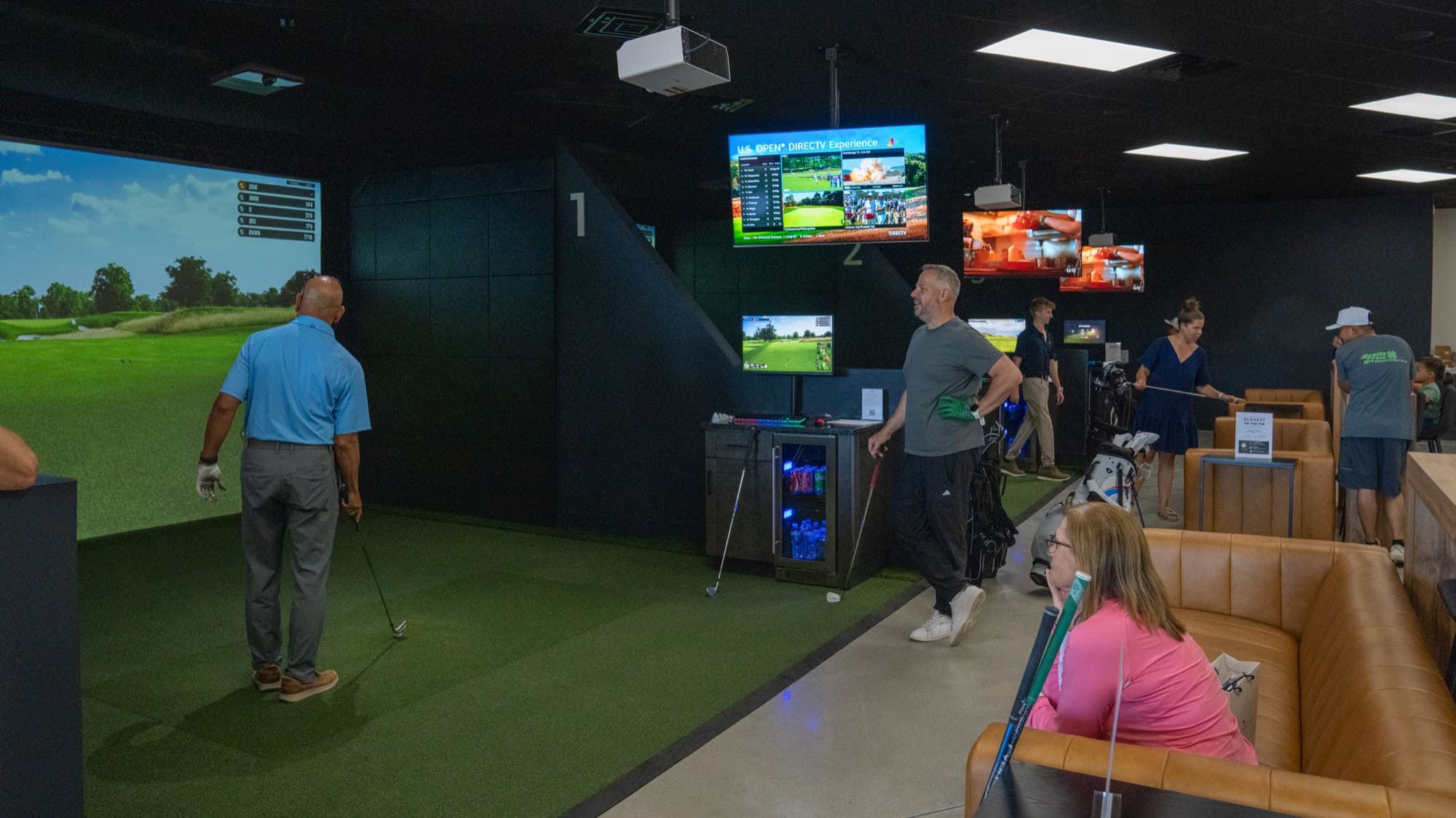 Guests playing across multiple simulator bays at Unbound Golf