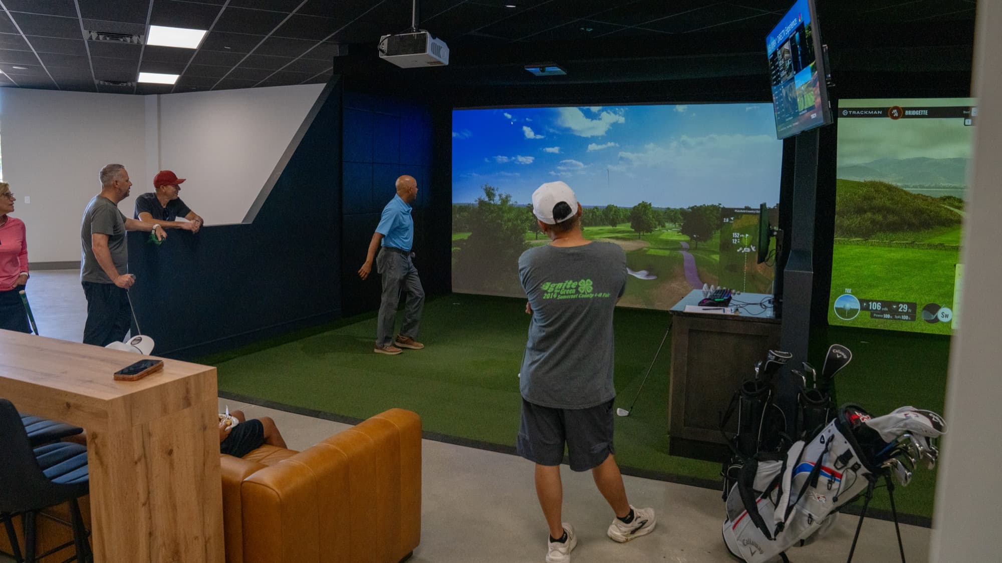 A golf pro sharing tips with guests in a simulator bay at Unbound Golf