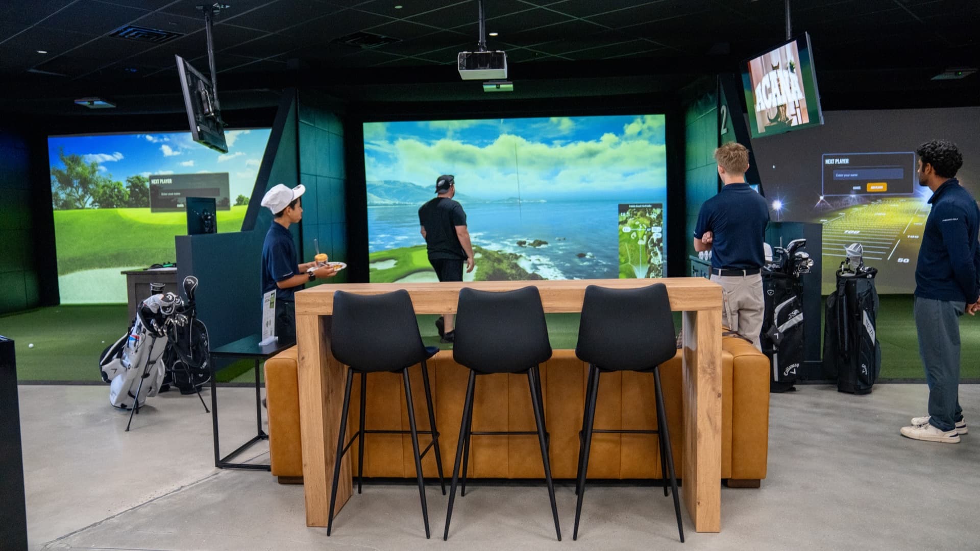 Unbound Golf indoor simulator lounge with Trackman bays, seating, and golfers